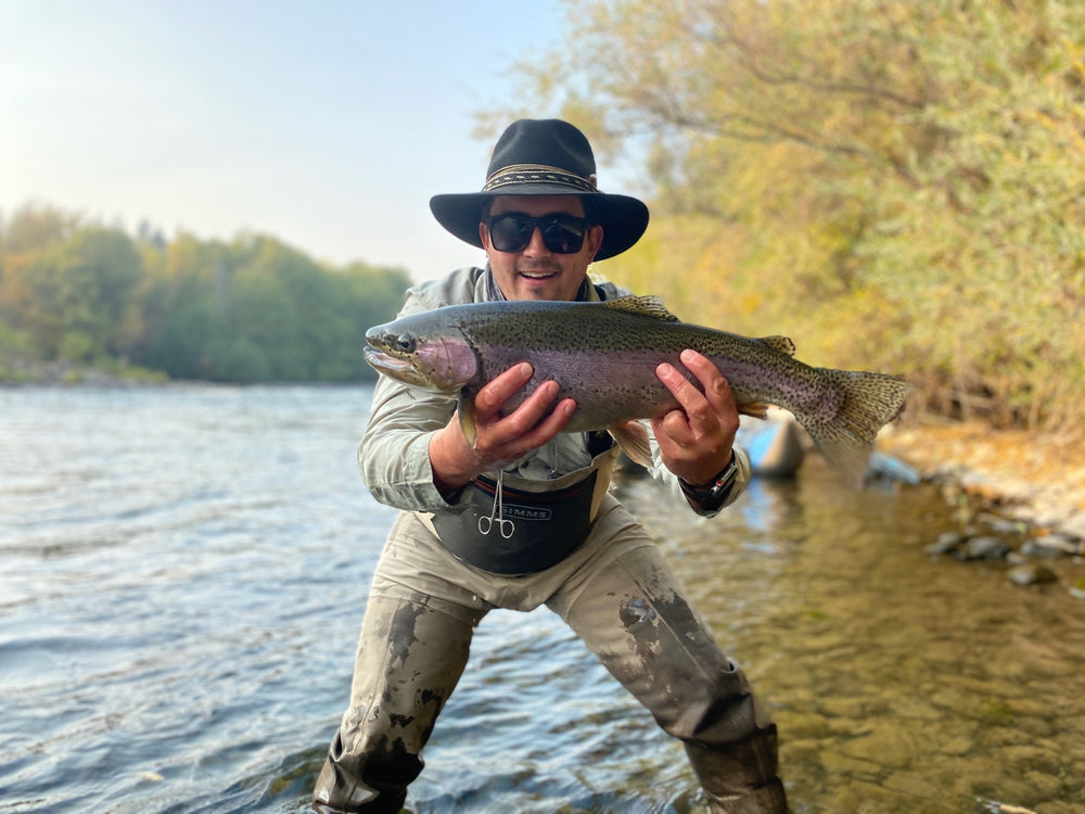 Angler proudly bracing a large trout in the river