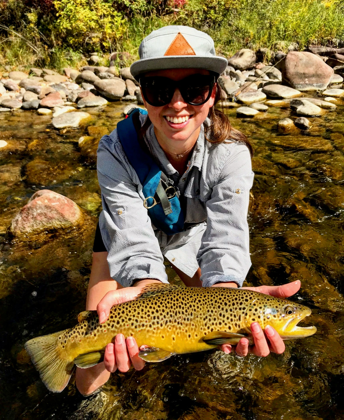 A woman presenting her brown trout beside the river