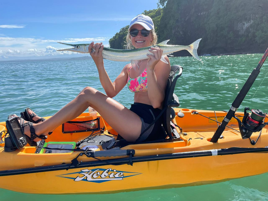 A woman smiling with a long saltwater catch from her kayak