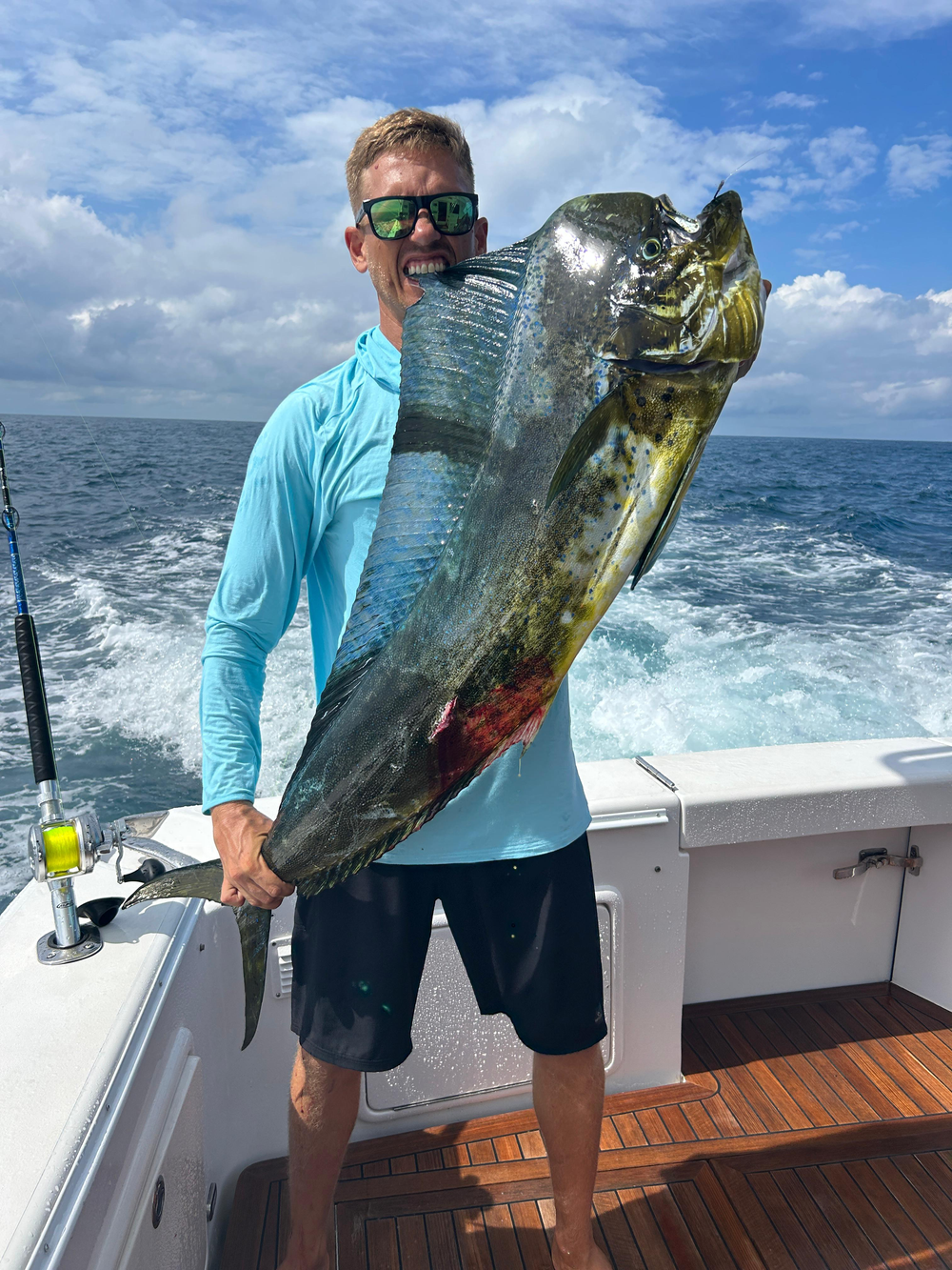 Offshore angler holding a towering mahi against the open sea