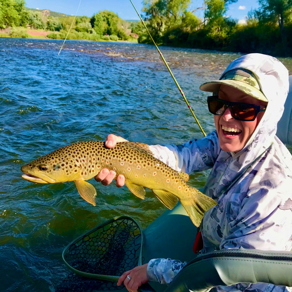 Joyful angler presenting a brown trout from a boat